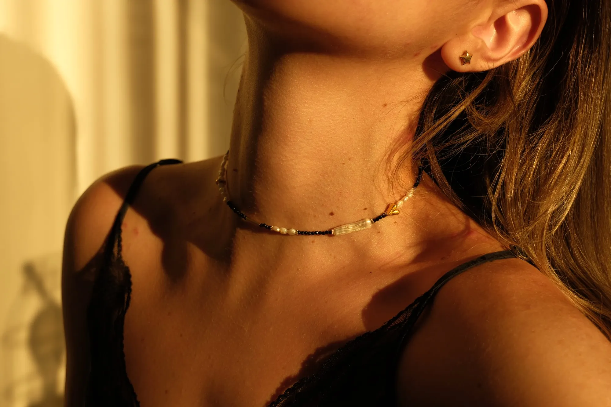 The Busy necklace worn in late golden light — black lapis lazuli, pearls and gold
